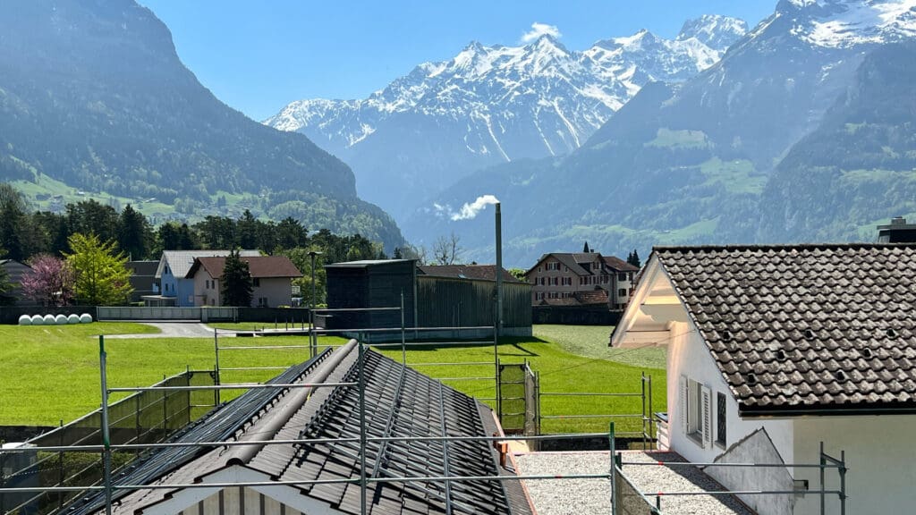 Foto: Sicht ins Reusstal richtung Süden, im Vordergrund ein Haus, auf dessen Dach Solarzellen montiert werden